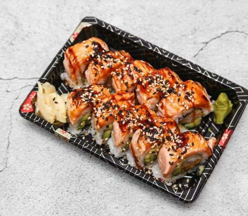 Seared salmon uramaki roll topped with sesame and teriyaki